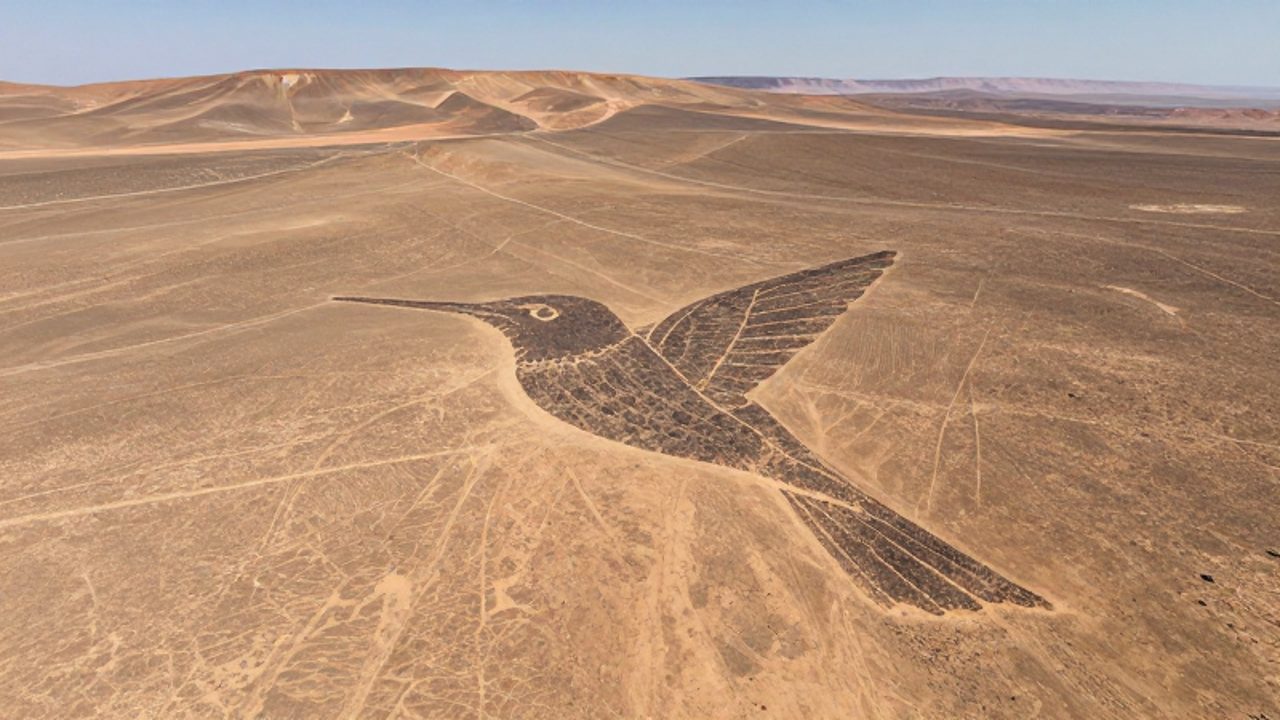 Vista aérea de un gran geoglifo con la forma de un colibrí trazado sobre el terreno árido y pedregoso de las pampas de Nazca.