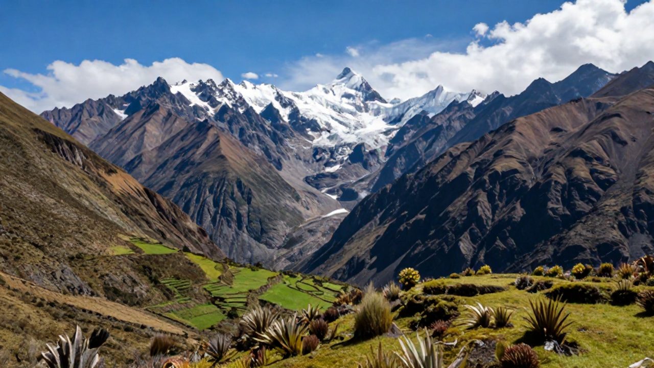 Paisaje de la cordillera de los Andes en Perú con valles verdes y terrazas que ascienden hacia picos nevados y glaciares bajo un cielo despejado.