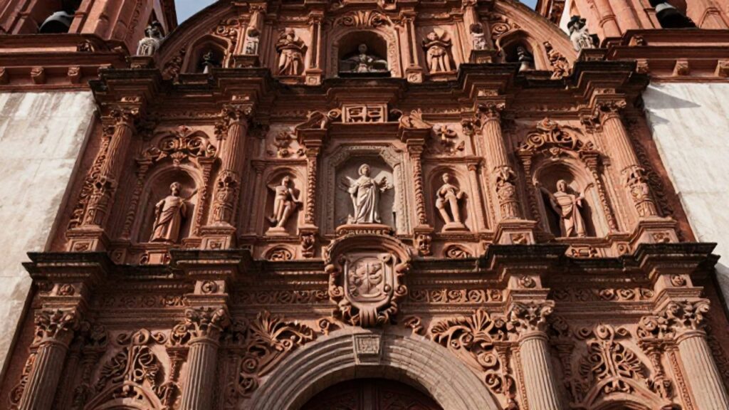 Detalle de la fachada de una iglesia con estilo barroco mestizo, donde se entrelazan iconografía religiosa y motivos de la flora andina tallados en piedra.