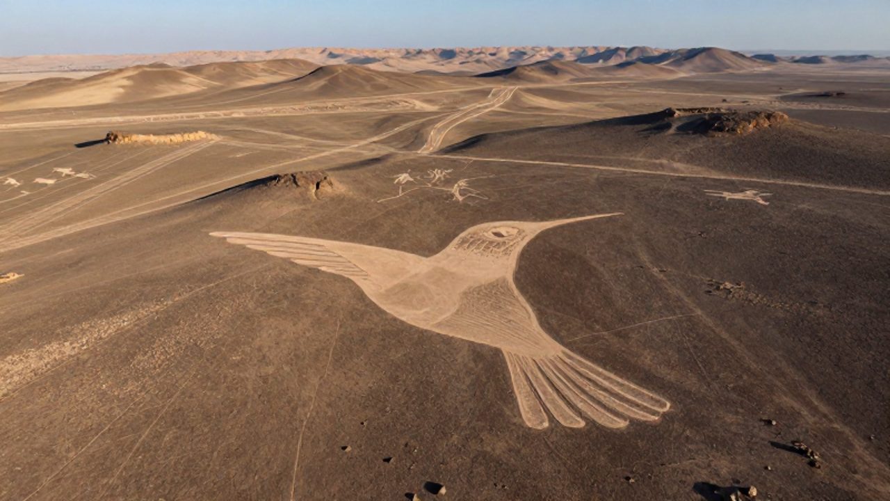 Vista aérea del geoglifo de un colibrí trazado en la superficie de la pampa de Nazca, rodeado de líneas geométricas en el desierto de Perú.