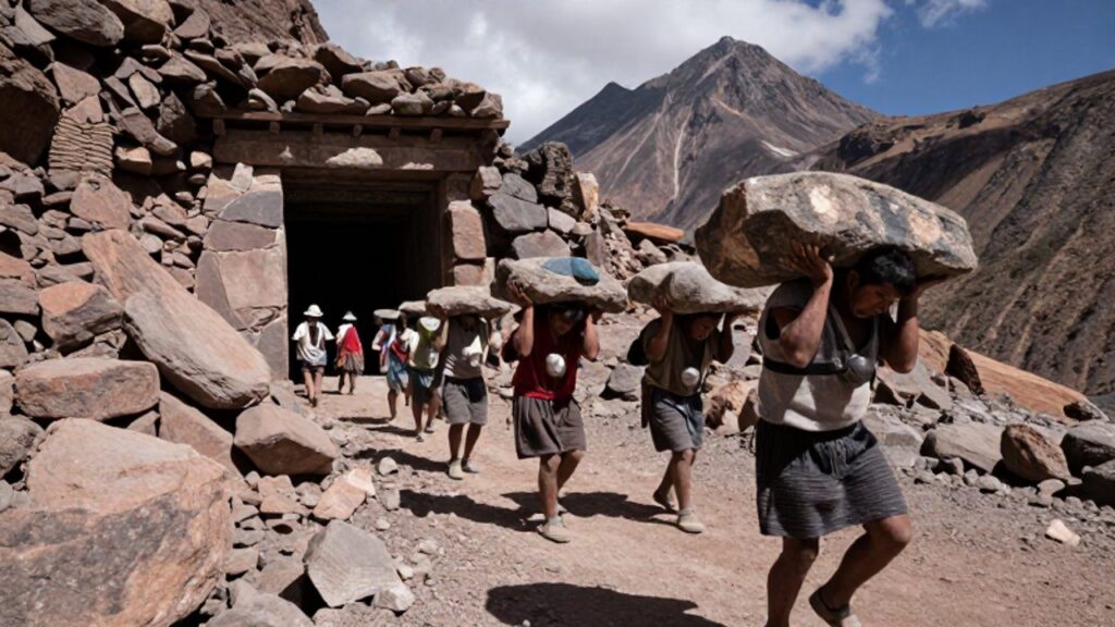 Hombres indígenas con vestimentas tradicionales cargan pesados sacos y piedras en un paisaje montañoso frente a la entrada de una mina colonial.